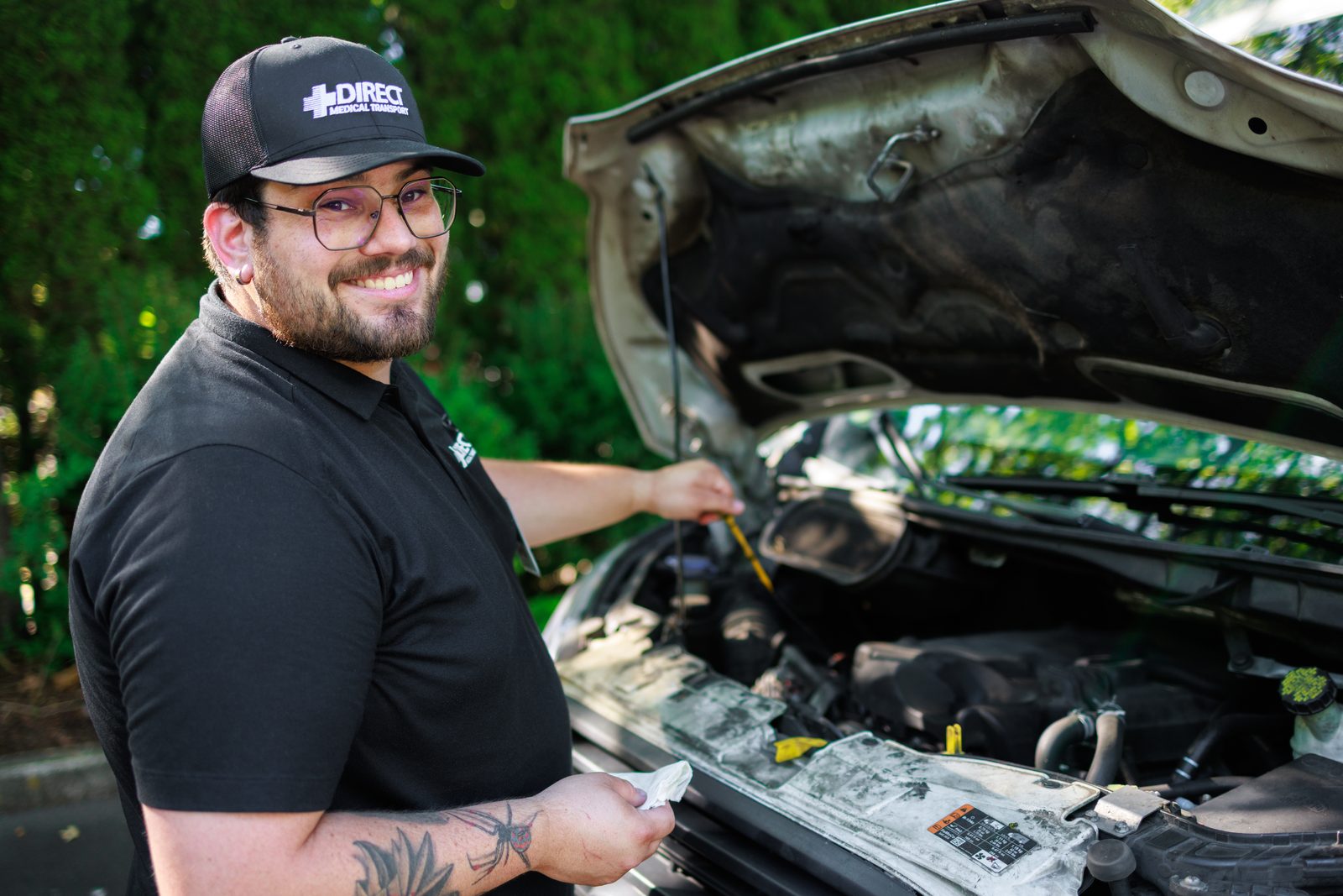 Direct Medical Transportation technician performing an in-house fluid check and safety inspection on a fleet vehicle