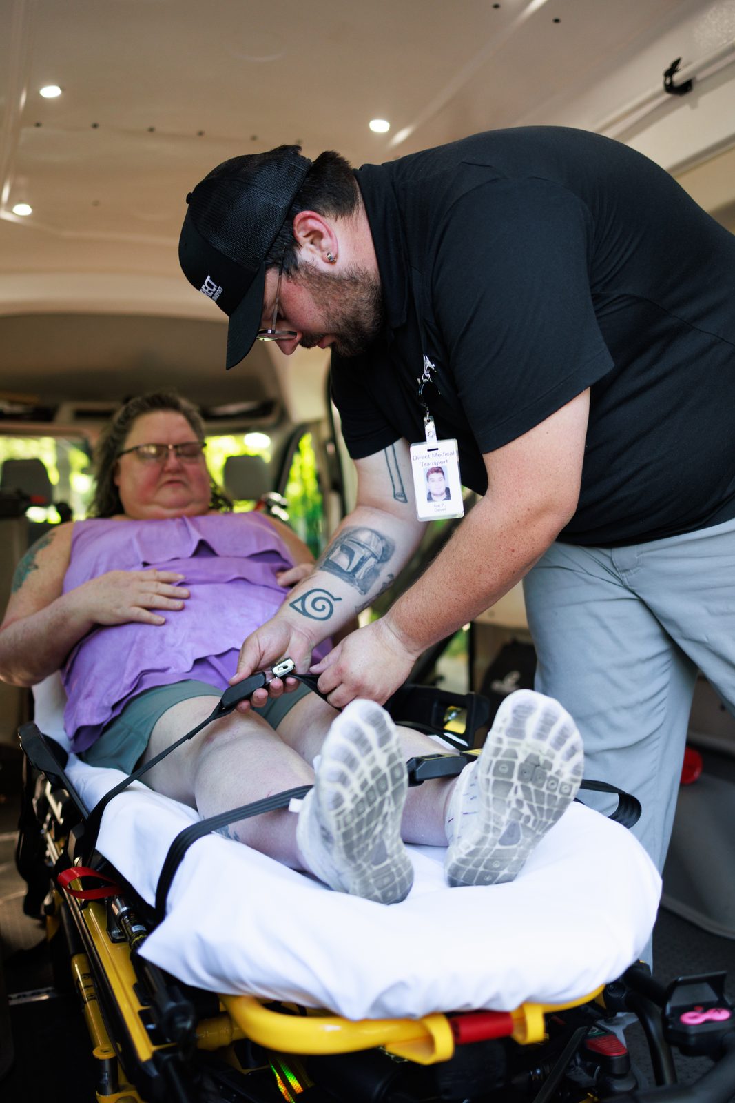 Direct Medical transportation attendant securing a patient on a gurney with safety straps before transportation