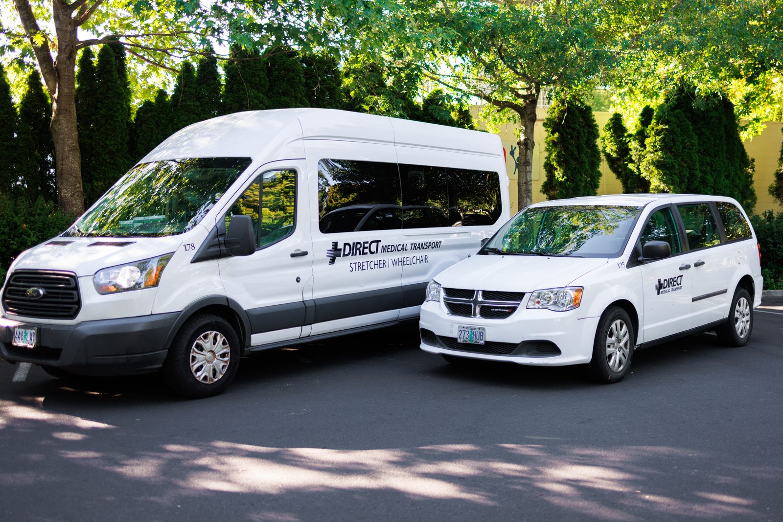 Direct Medical transportation fleet vehicles, a stretcher and wheelchair van alongside an accessible minivan, parked in Eugene, Oregon